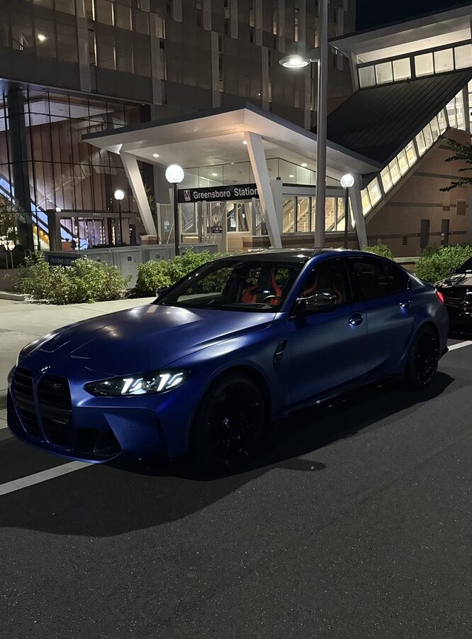 BMW M3 Competition xDrive in Frozen Portimao Blue parked in a concrete parking garage